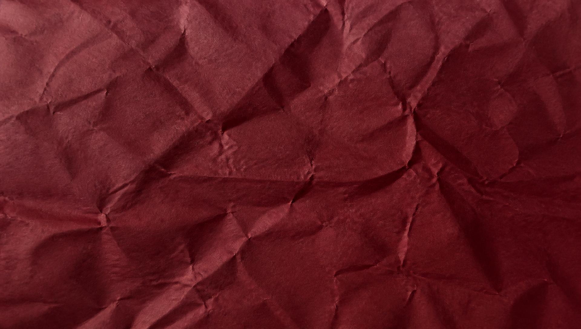 Slightly crinkled maroon paper lit by raking light