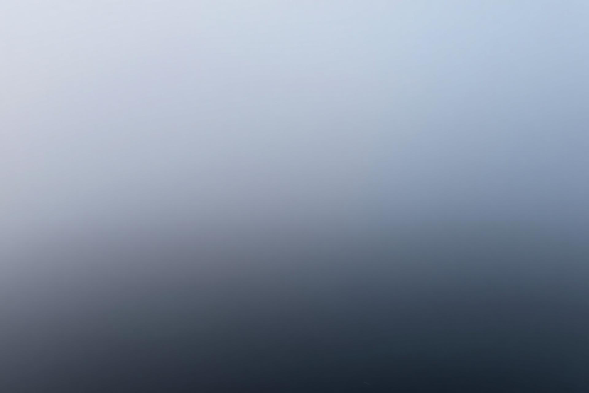 Fog drifting over still water at dawn